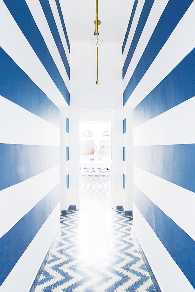 Narrow Hallway with Blue Chevron Pattern Floor and Bold Stripe Walls