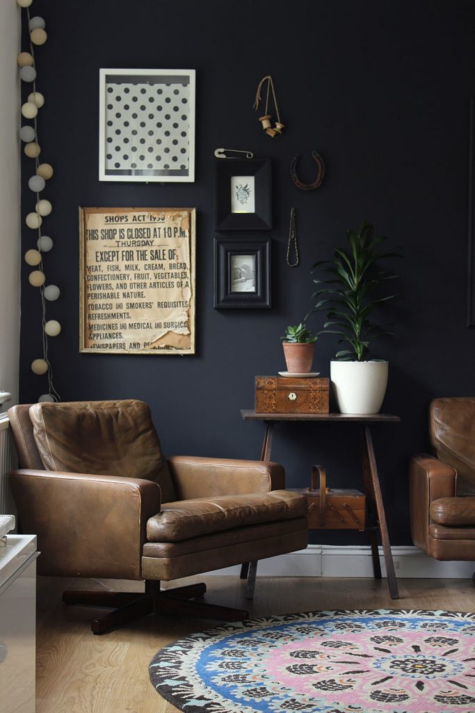 A black wall with a brown leather chair and small side table.